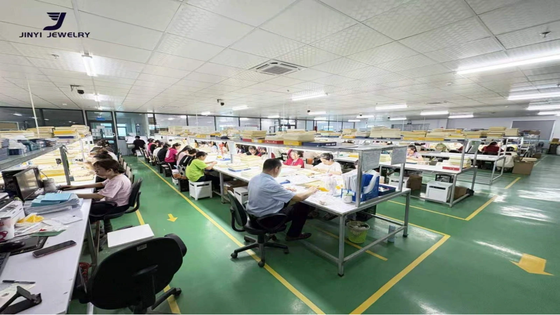 Company-supplied photograph showing JINYI Vietnam jewelry manufacturing workstations and production scale.